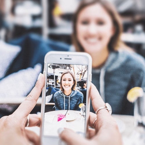 Person macht mit Smartphone Foto von einer Frau