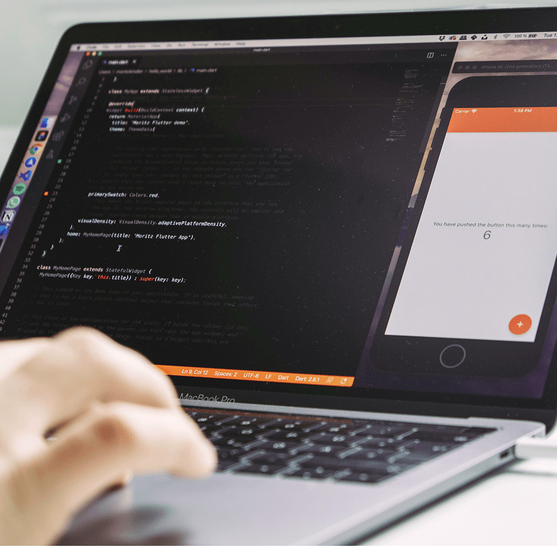 Entwickler tippt Code auf Tastatur mit gro&szlig;em Bildschirm im Vordergrund